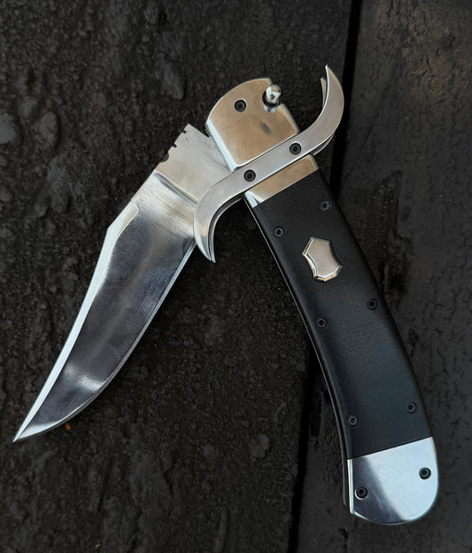 Folding knife with a black handle and silver blade on a dark textured surface