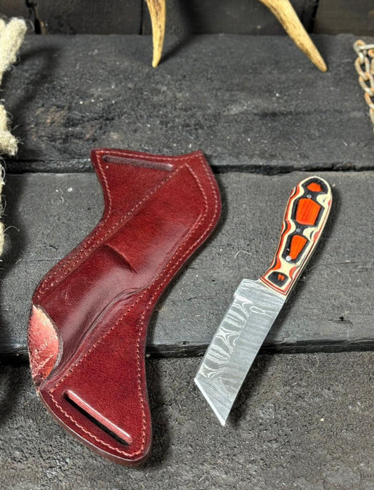 Red leather holster and decorative knife on a dark surface