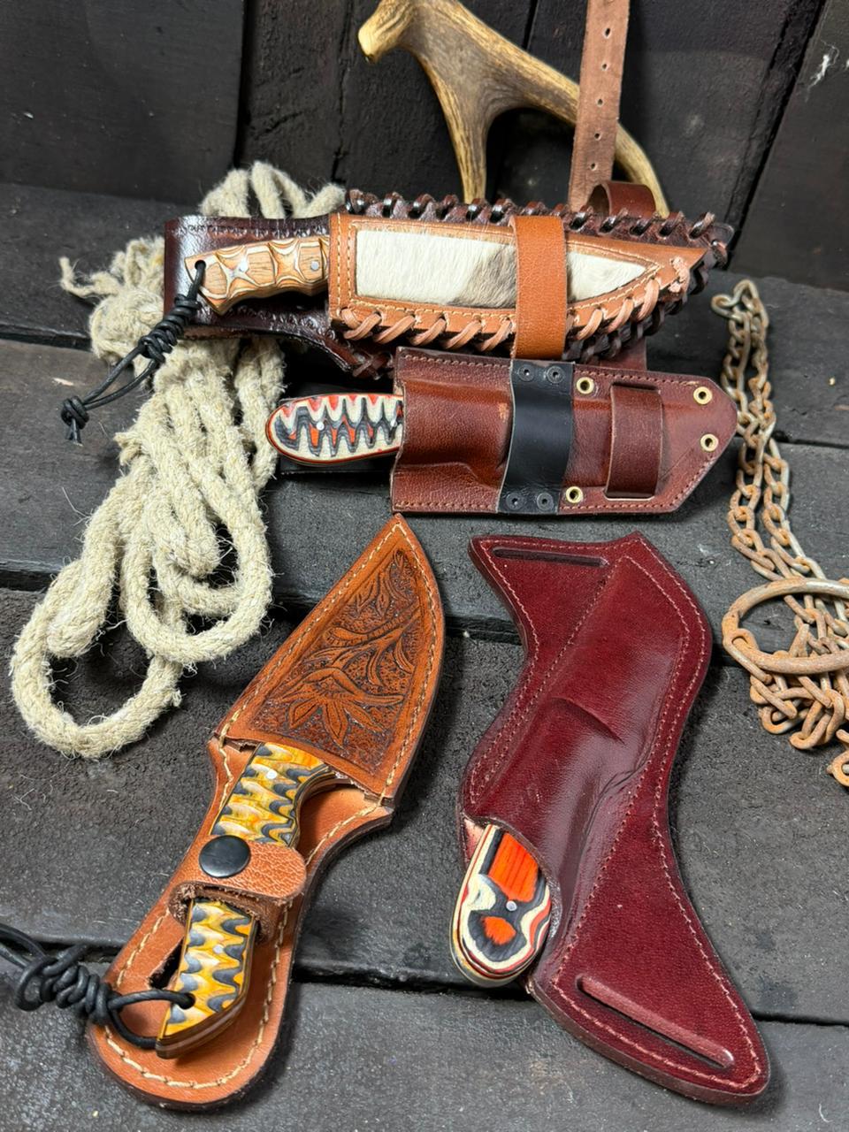 Collection of intricately designed leather sheaths on a dark surface