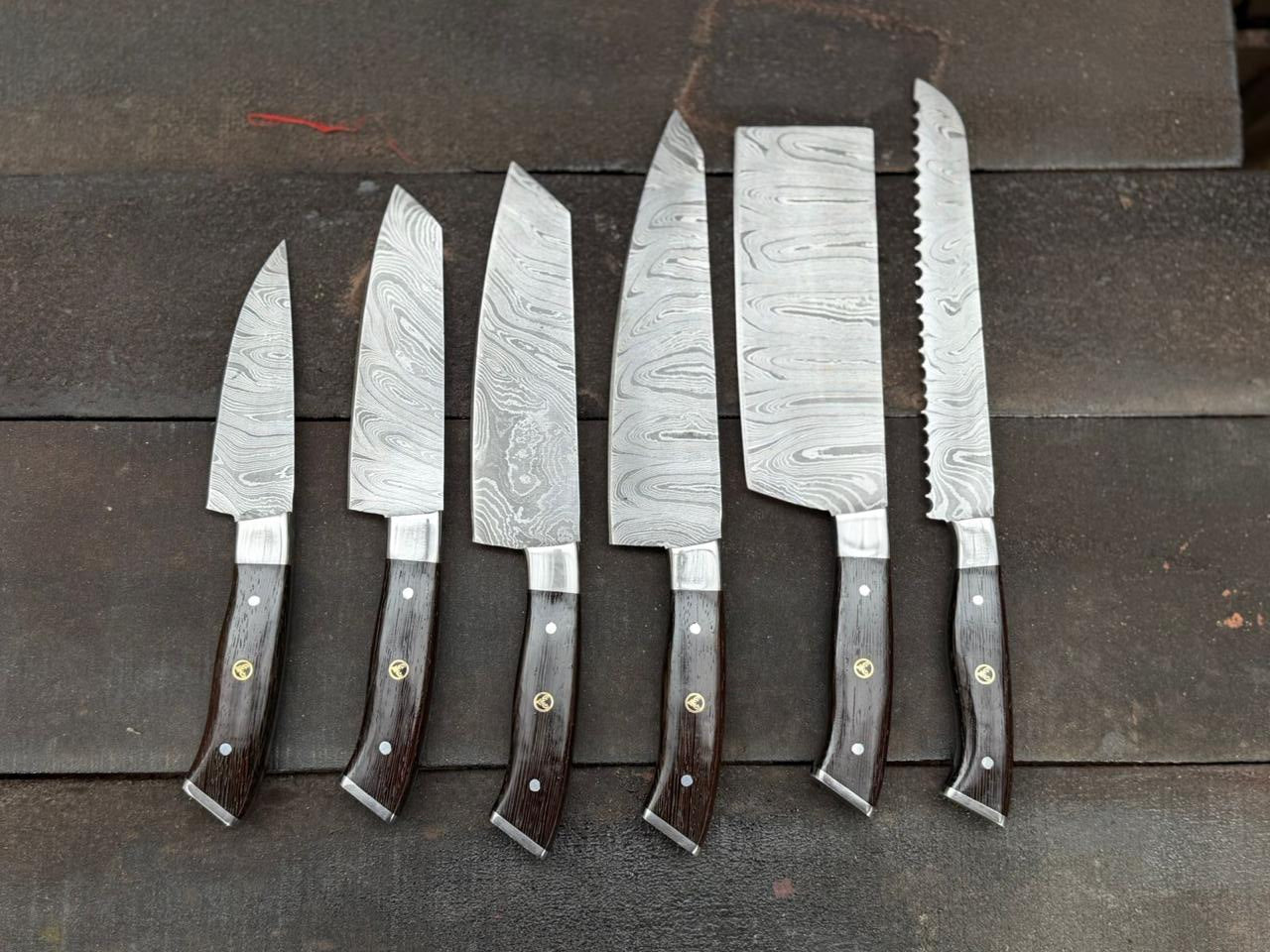 Set of six Damascus steel kitchen knives with wooden handles on a dark wooden surface