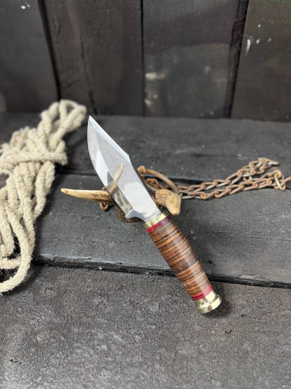 Decorative knife with wooden handle and chain on a dark surface