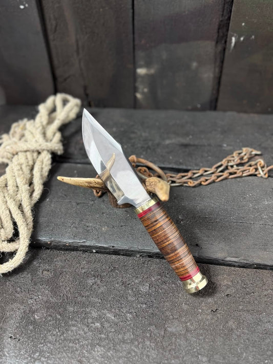 Decorative knife with wooden handle and chain on a dark surface