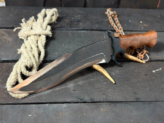Knife with wooden handle and metal blade on a dark surface with rope and antlers.