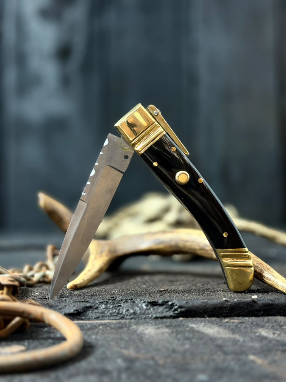 Foldable knife with gold accents on a dark surface