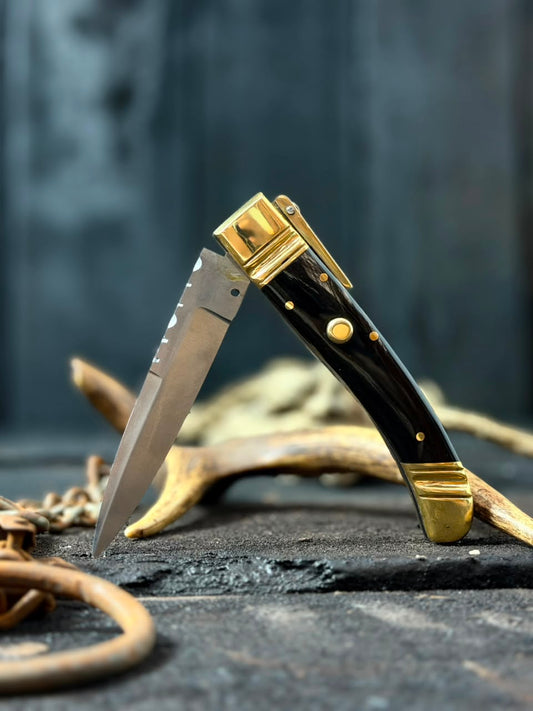 Foldable knife with gold accents on a dark surface