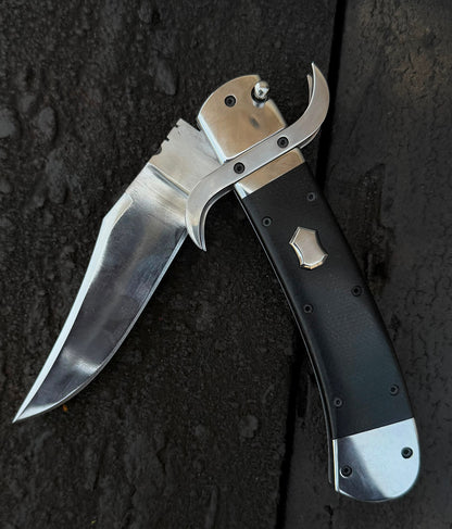 Folding knife with a black handle and silver blade on a dark textured surface