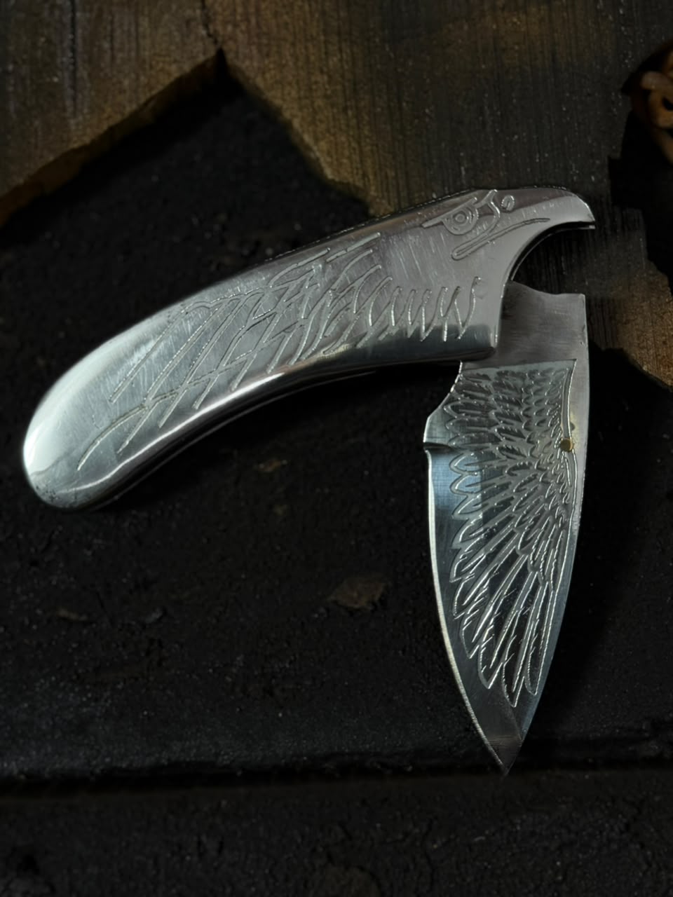 Folding knife with engraved design on a dark surface