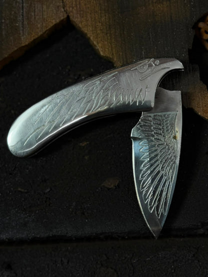 Folding knife with engraved design on a dark surface