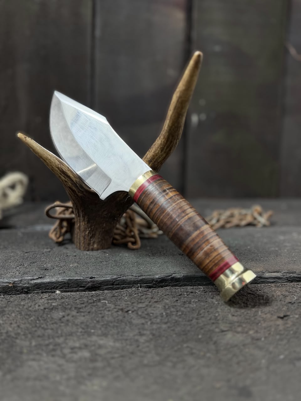 Knife with wooden handle and metal sheath on a textured surface