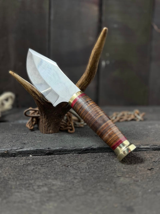 Knife with wooden handle and metal sheath on a textured surface