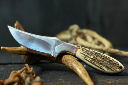 Knife with wooden handle on antlers against a dark background