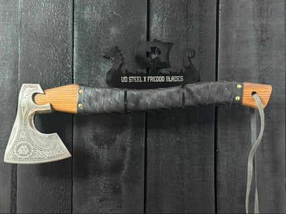 Decorative axe with wooden handle and metal blade on a dark wooden background