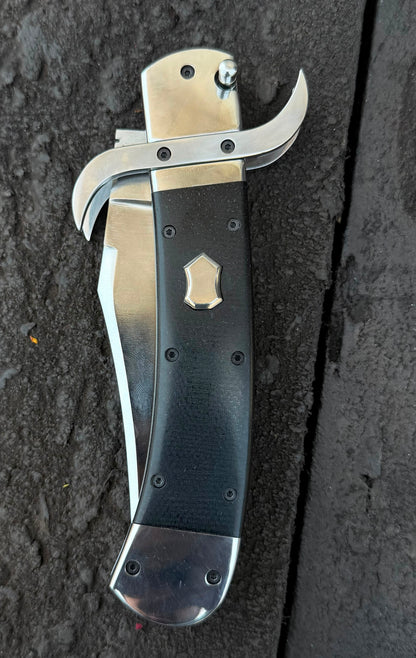 Folded knife with a black handle and silver blade on a dark textured surface