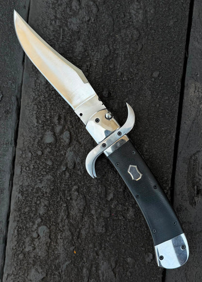Folding knife with a black handle on a dark textured surface