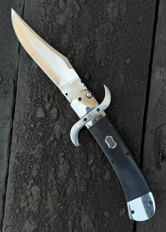 Folding knife with a black handle on a dark textured surface