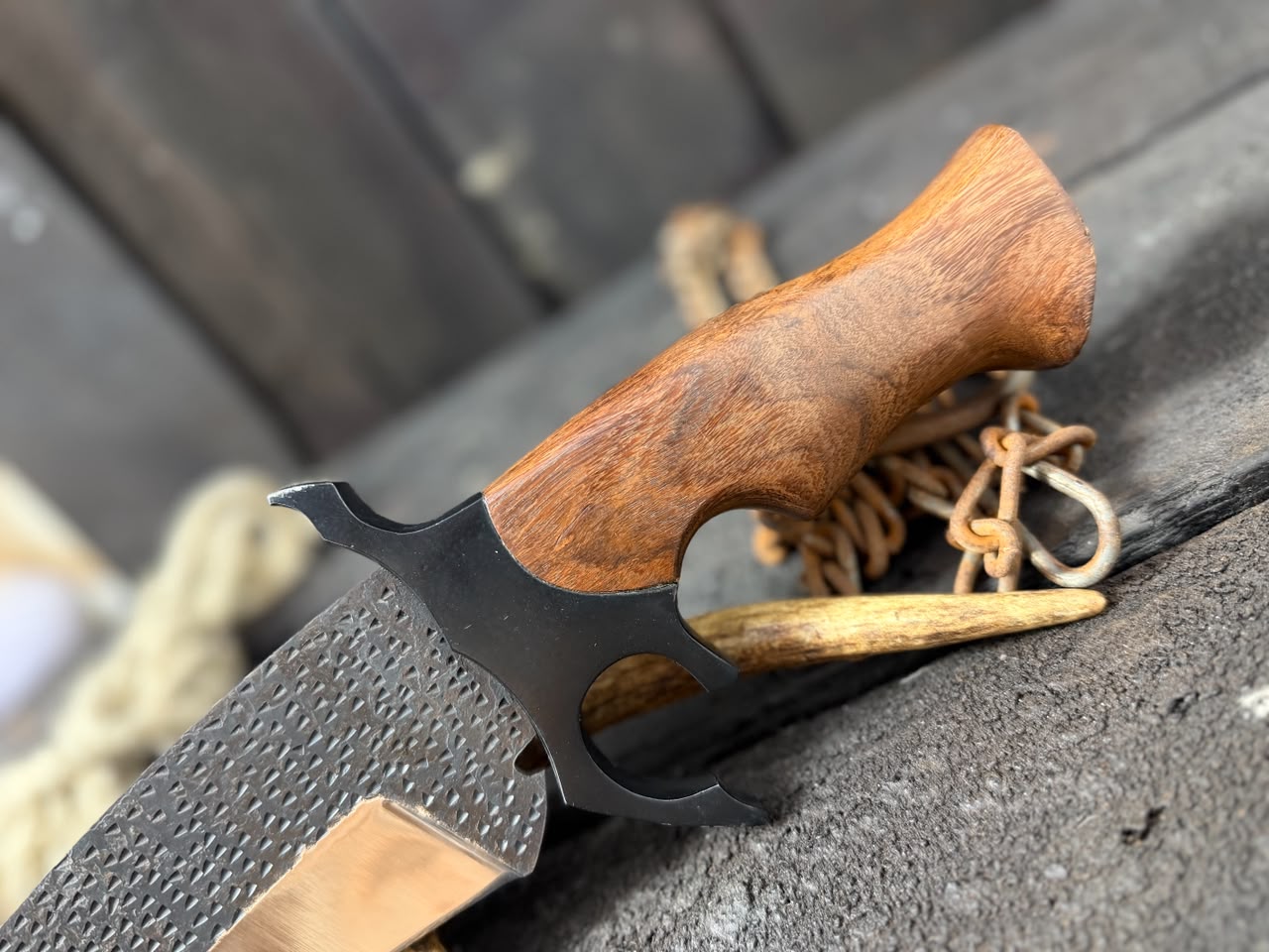Knife with wooden handle and black blade on a textured surface