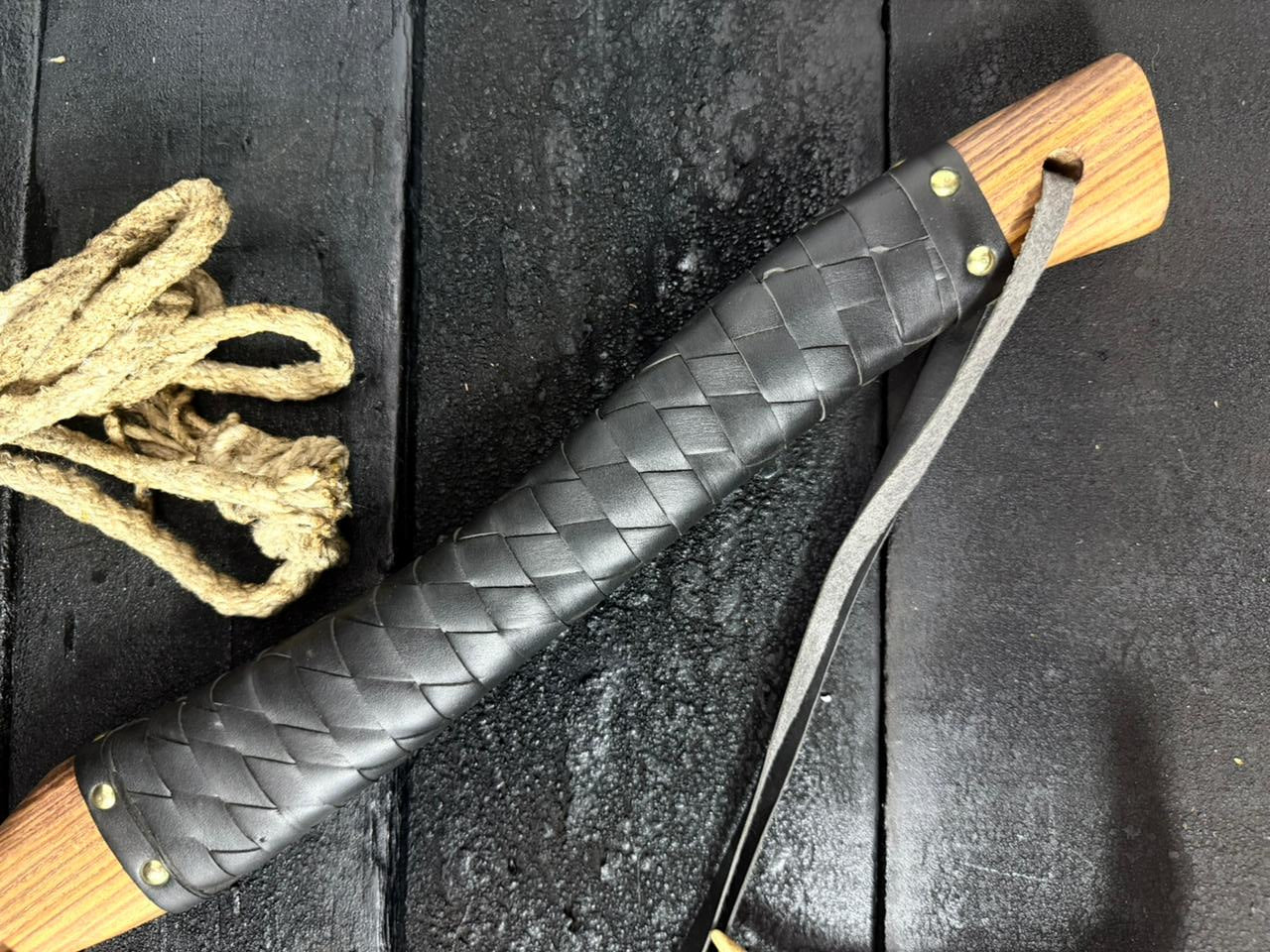 Black leather sheath with wooden handle on a dark surface