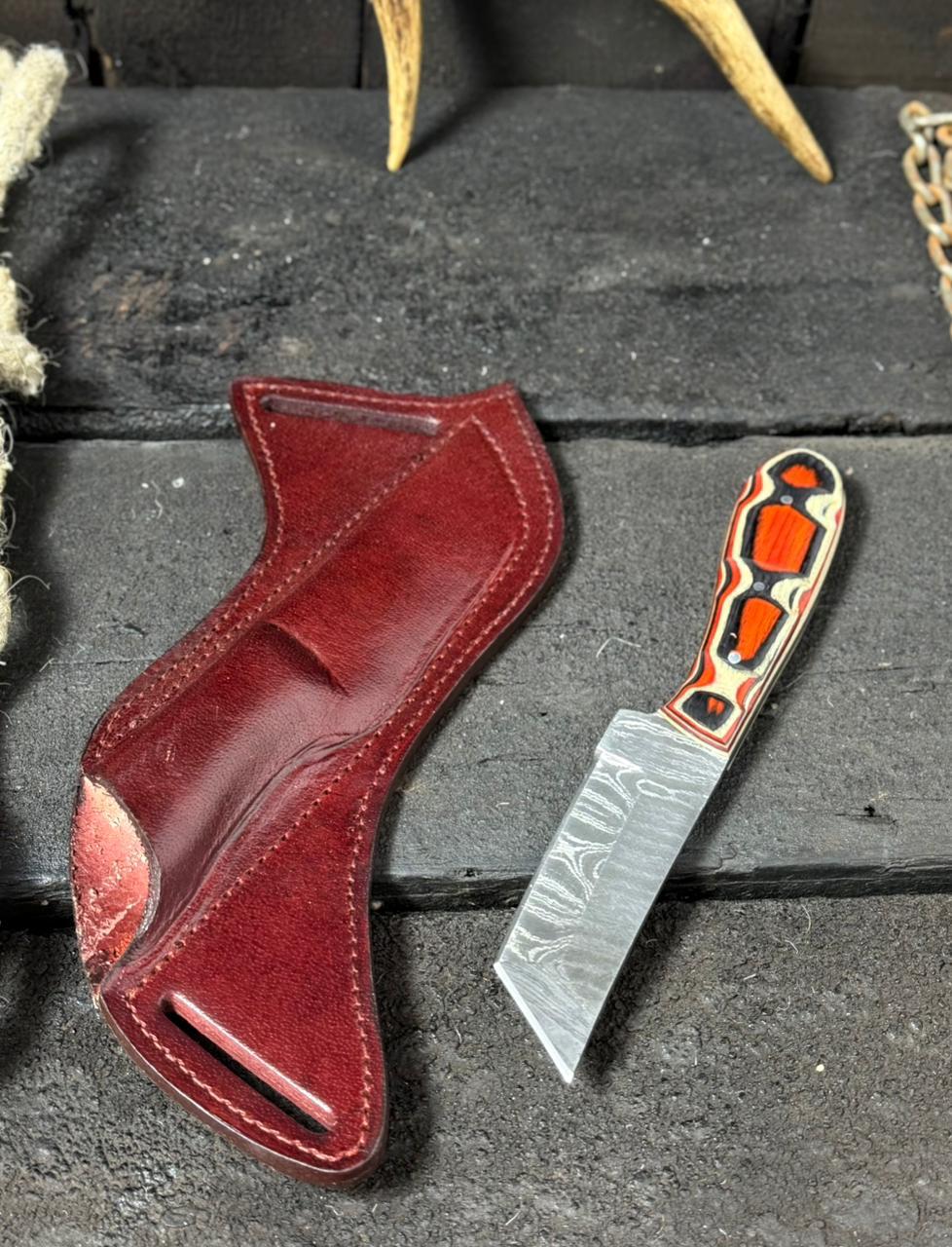 Red leather holster and decorative knife on a dark surface