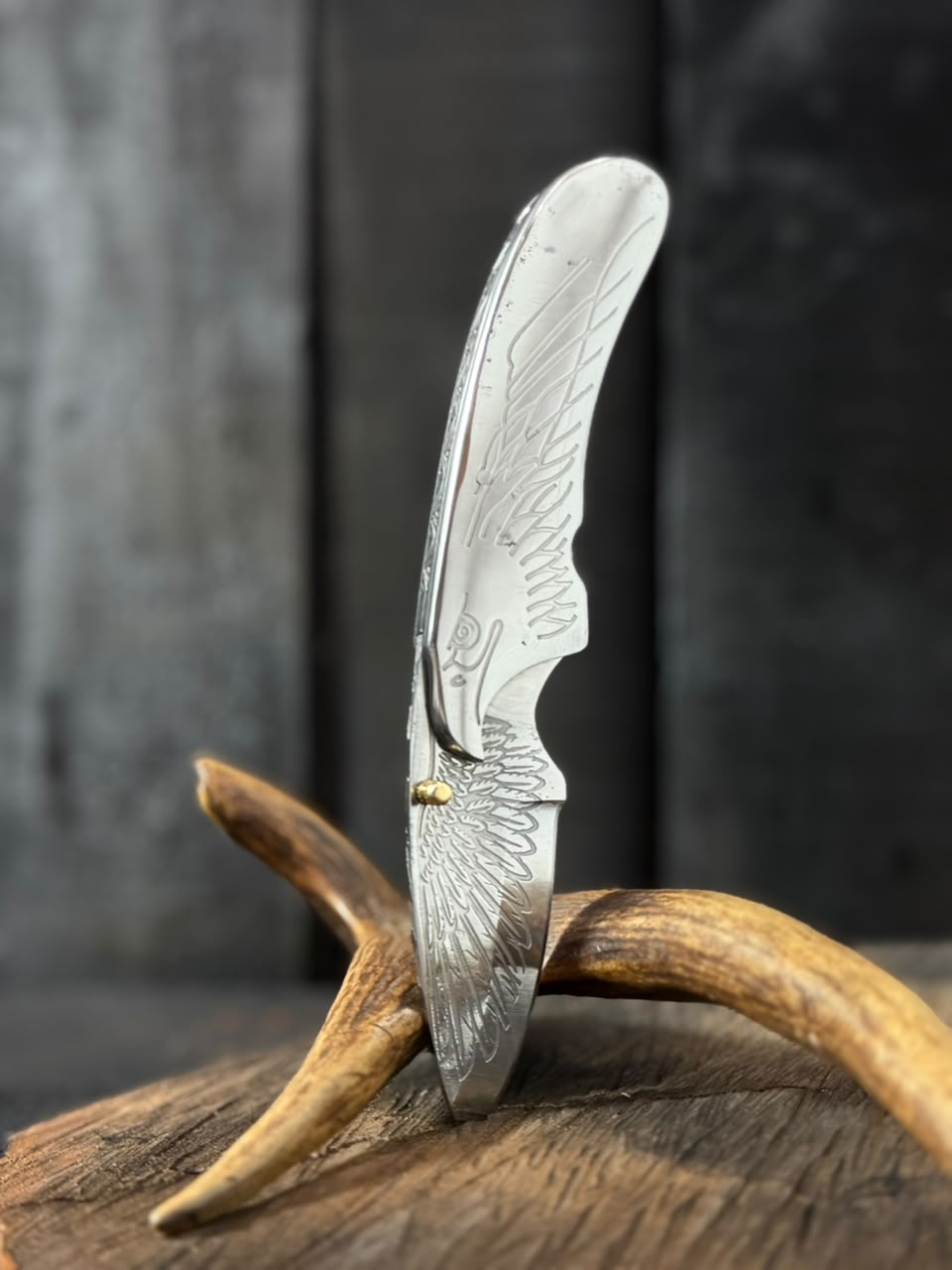 Folding knife with decorative blade on a wooden surface