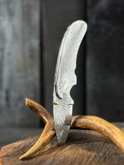 Folding knife with decorative blade on a wooden surface