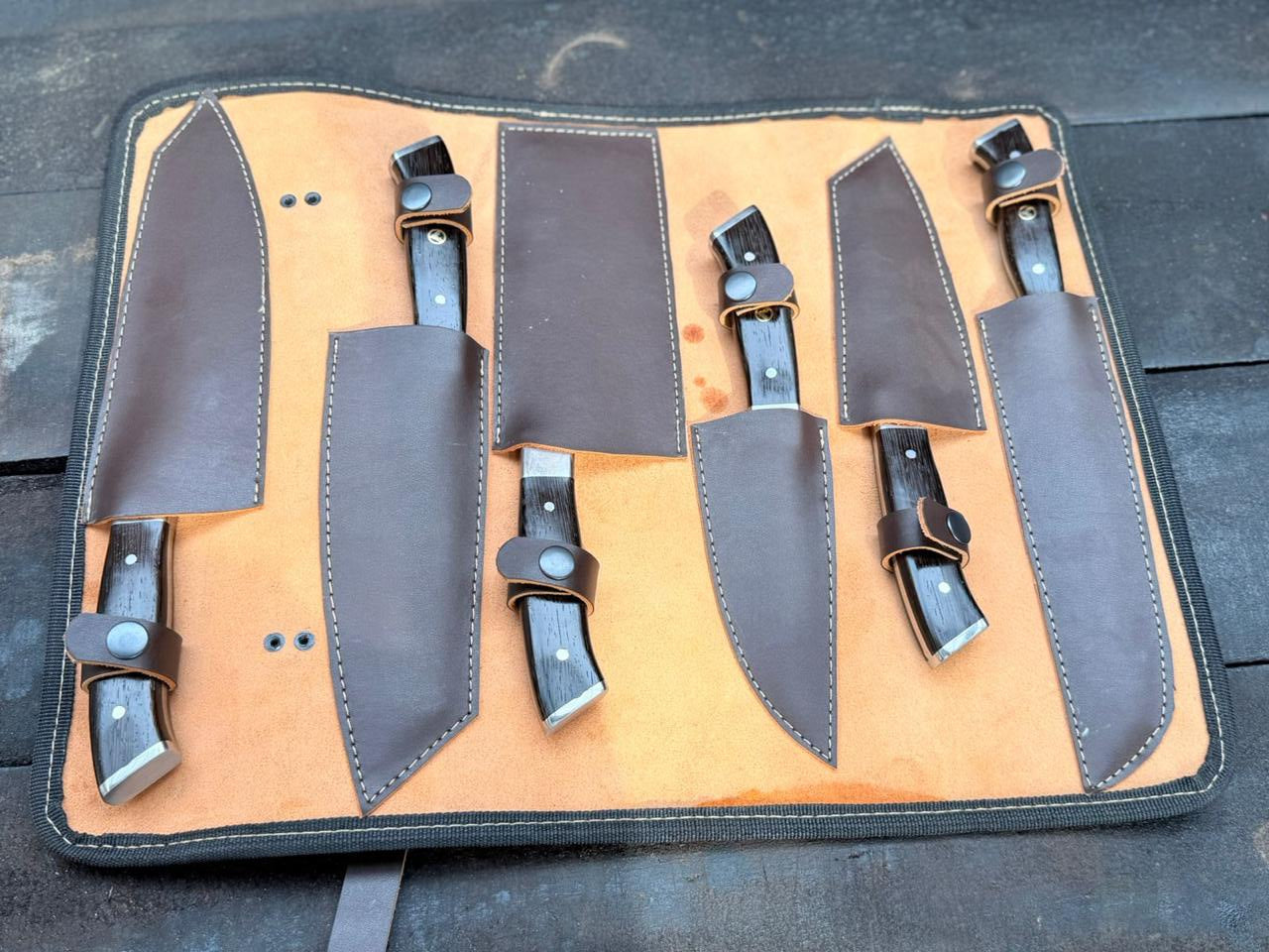 Set of knives in leather sheaths on a dark surface