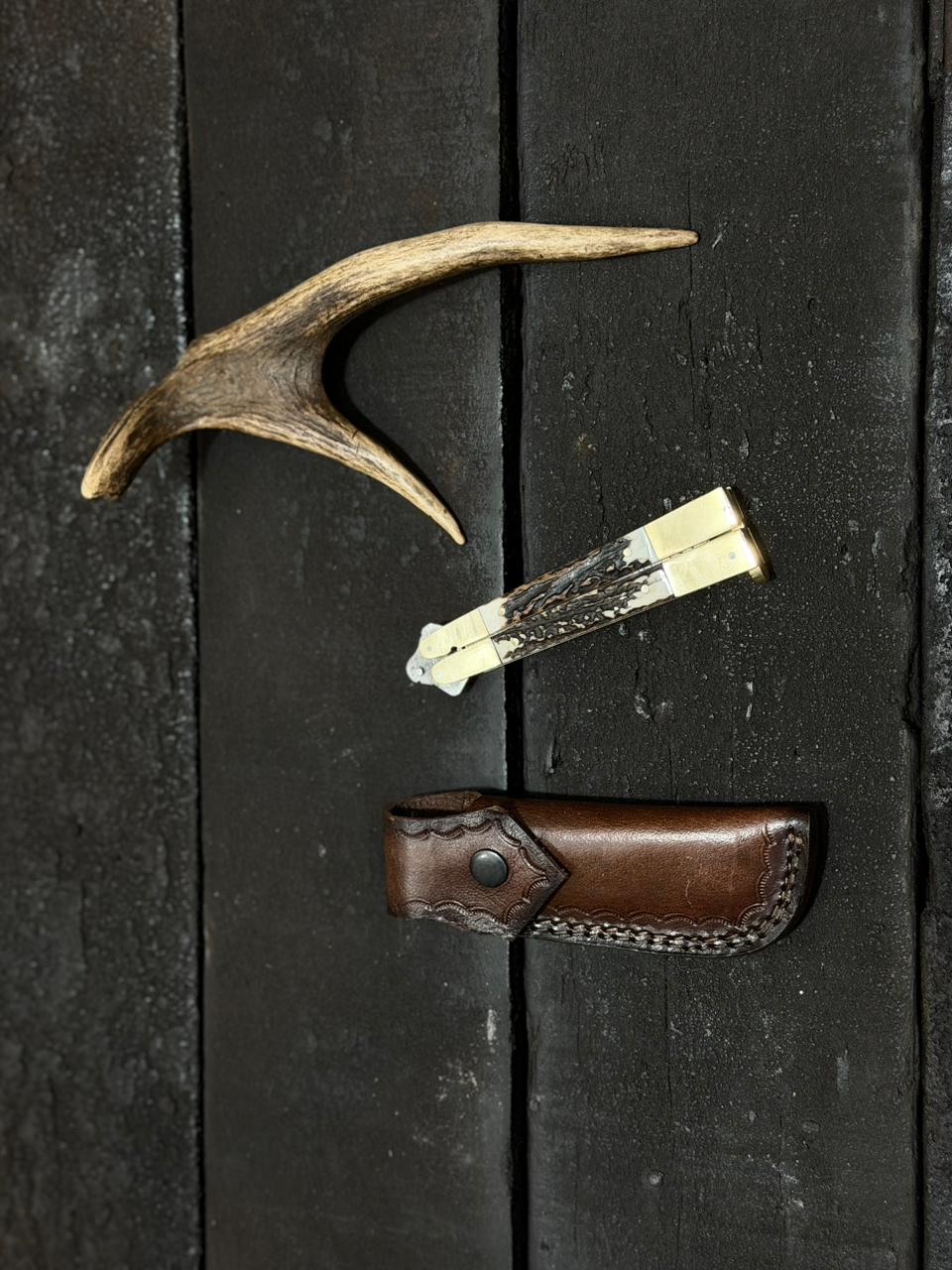 Antler and leather sheath on a dark wooden surface