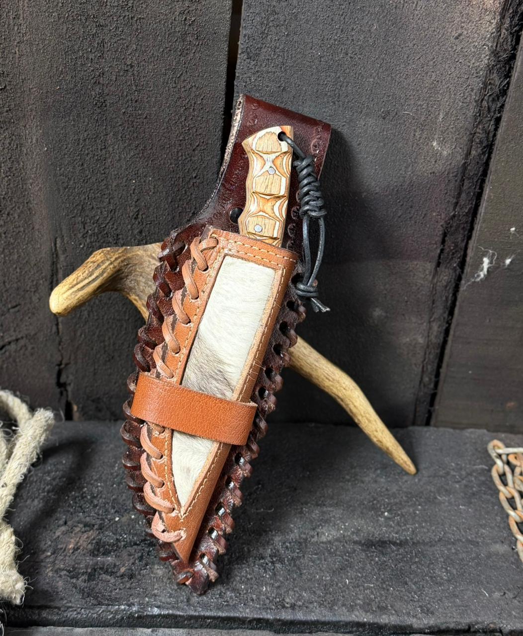 Decorative knife with leather sheath and wooden handle on a dark background