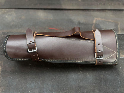 Brown leather boot with a strap on a textured gray background
