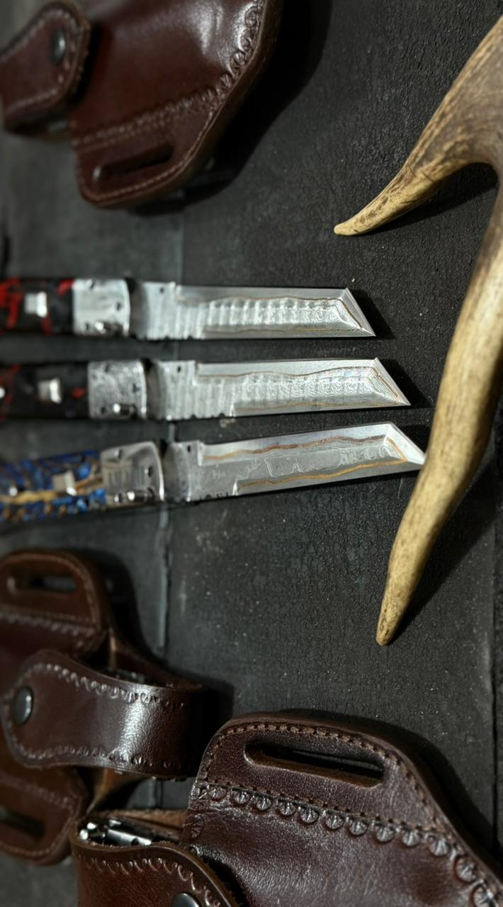 Set of hunting knives with leather sheaths on a dark surface
