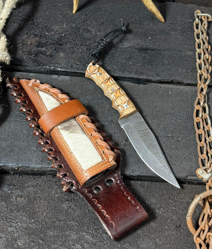 Decorative knife with leather sheath on a dark stone surface
