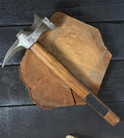 Wooden axe handle with metal head on a dark wooden surface