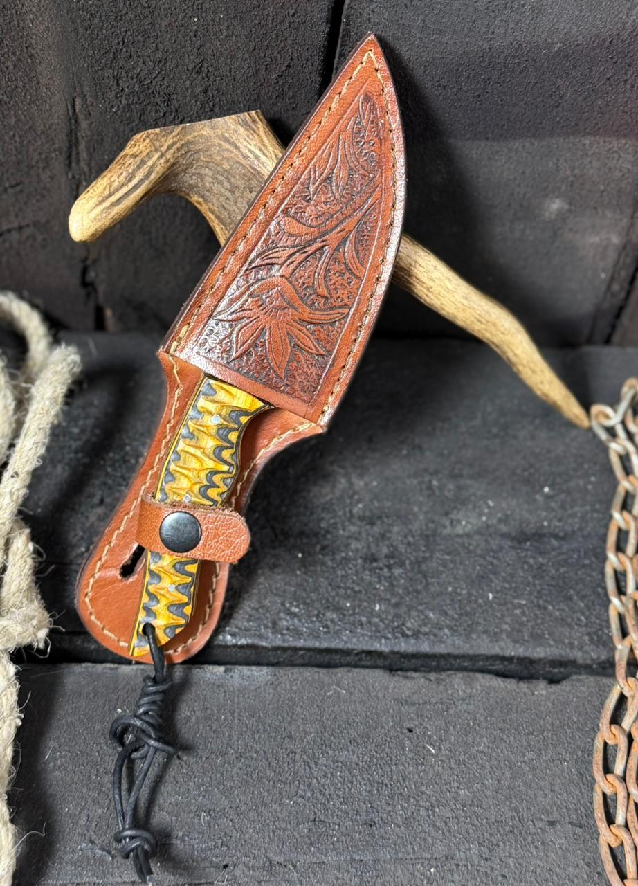 Decorative knife with leather sheath on a textured surface