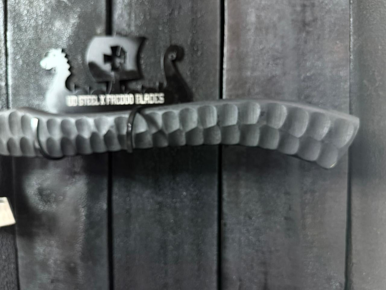 Decorative metal wall hook with a logo on a wooden background