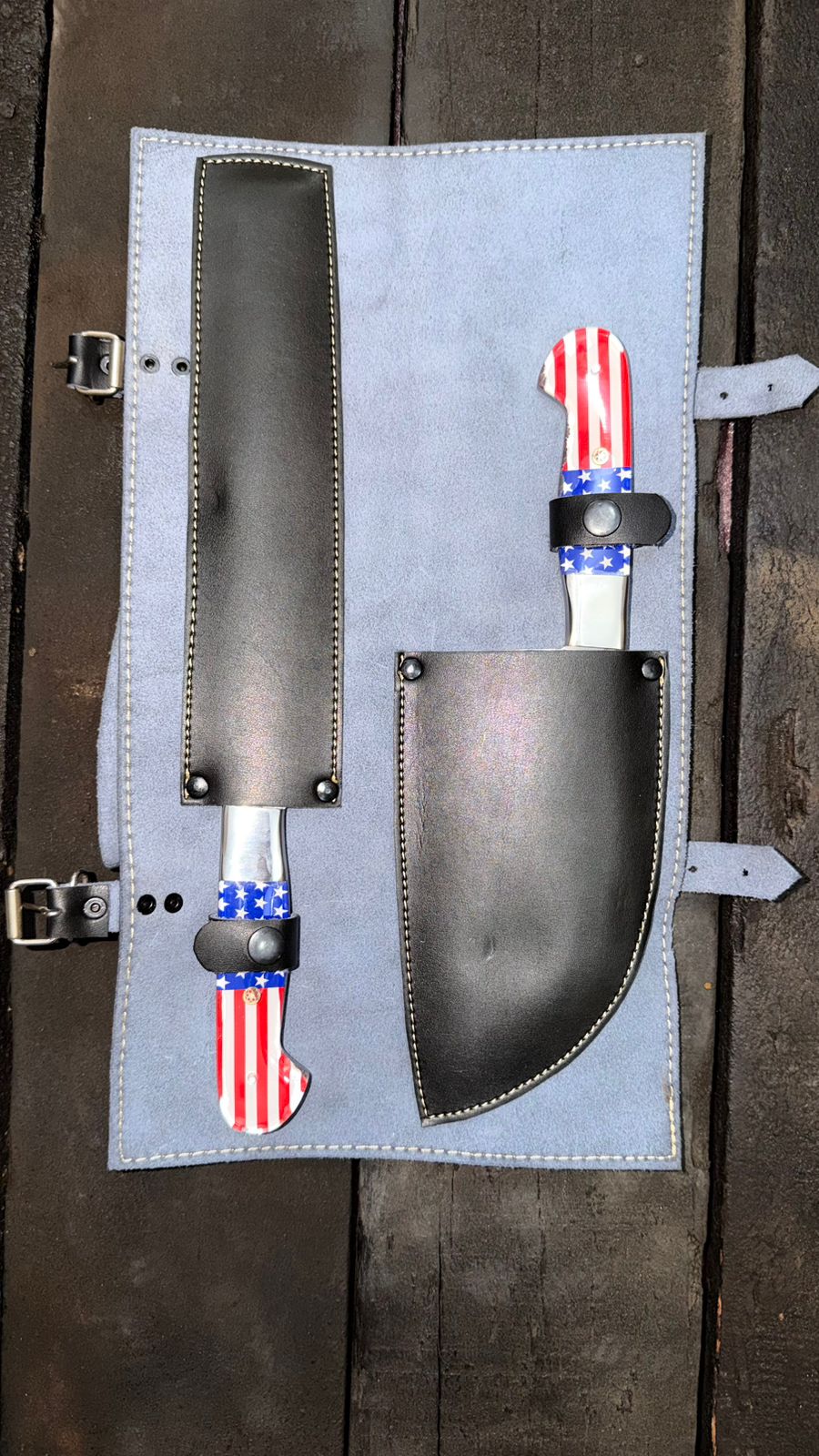 Set of knives with American flag designs on a gray leather sheath against a wooden background